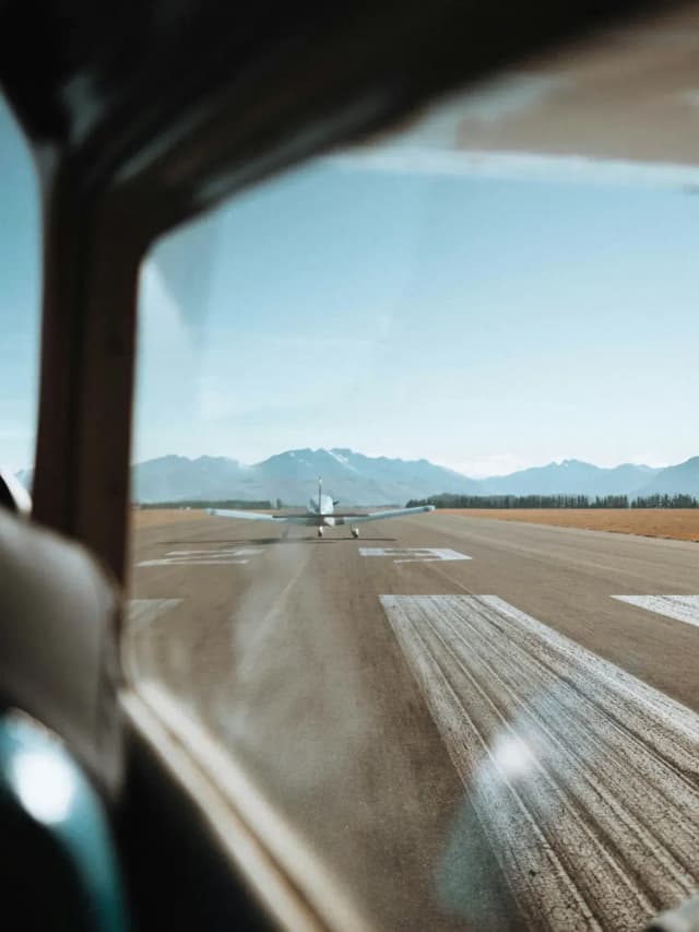 View from a plane window of a small aircraft on a runway.