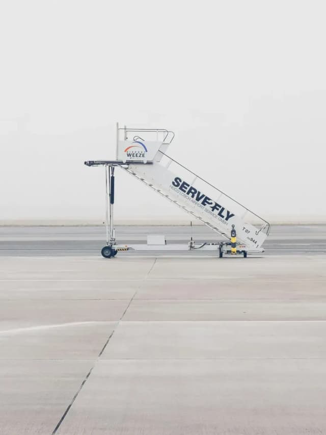 Mobile aircraft stairs on an empty airport tarmac.